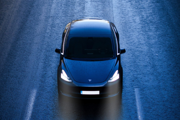 Tesla nera su strada vista dall'alto e frontale, in scherse condizioni di luminosità