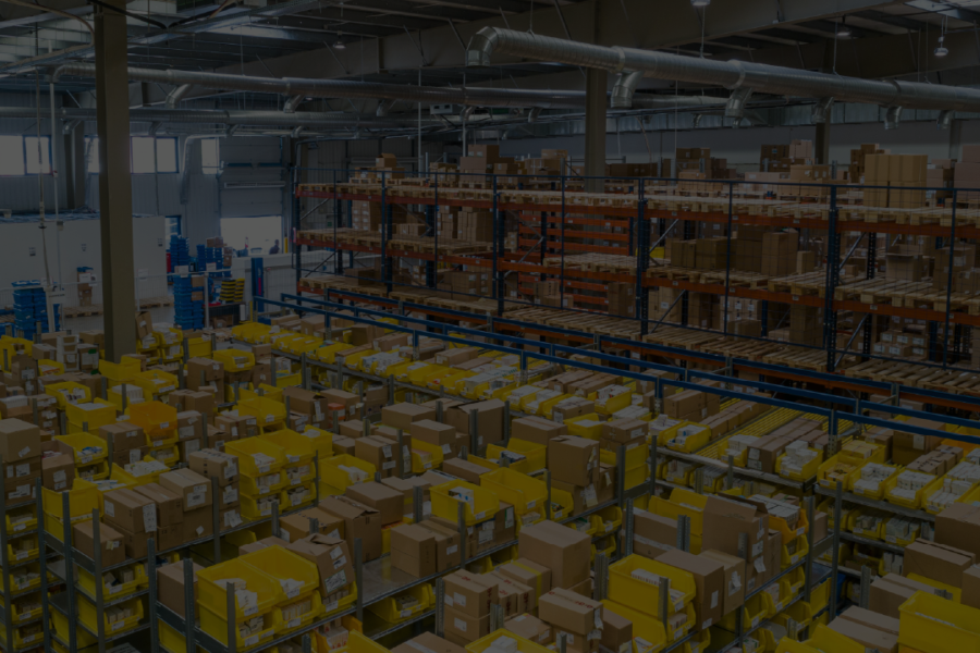 Magazzino Amazon visto dall'alto, con alti scaffali pieni di pacchi pronti per essere spediti