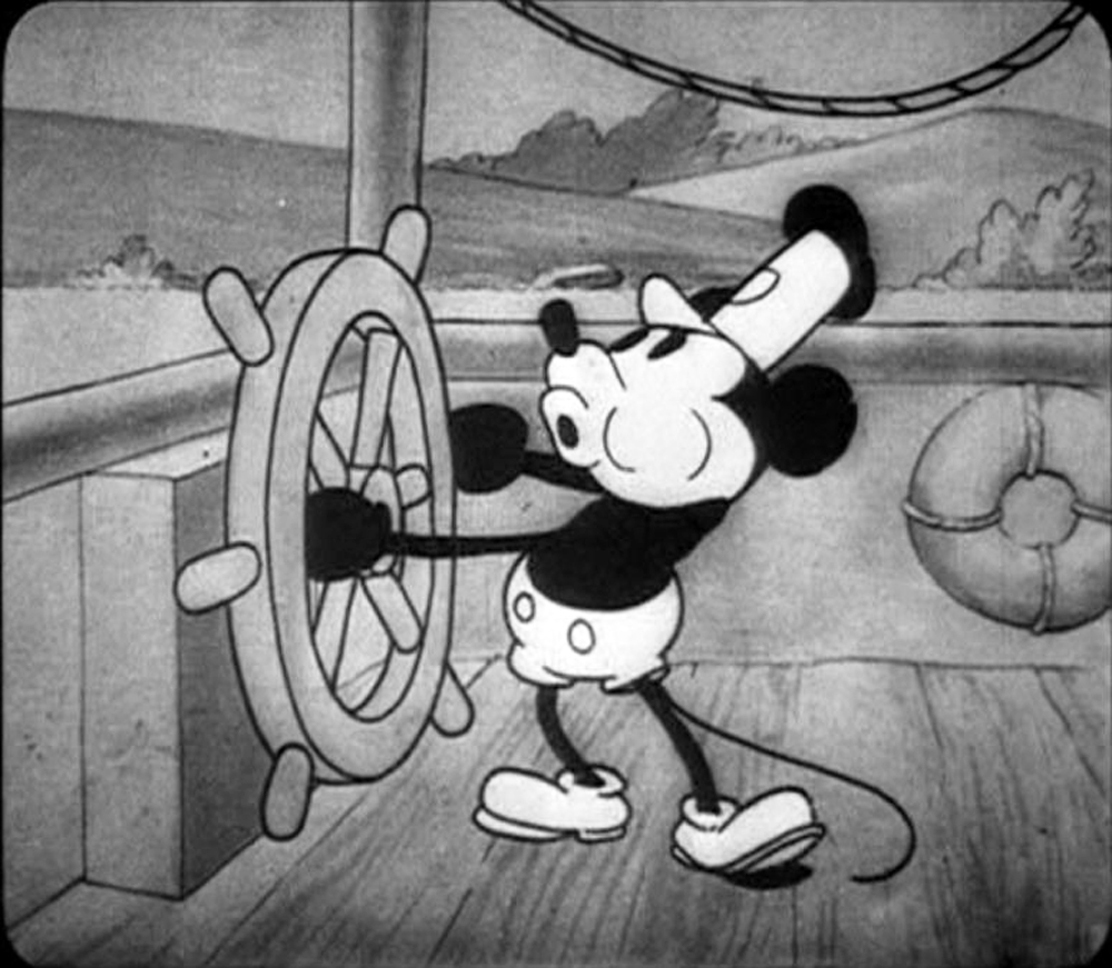 Scena iconica di Mickey Mouse che guida una nave in bianco e nero dal cartone animato Steamboat Willie del 1928, uno dei primi film d’animazione sonori creati da Walt Disney.